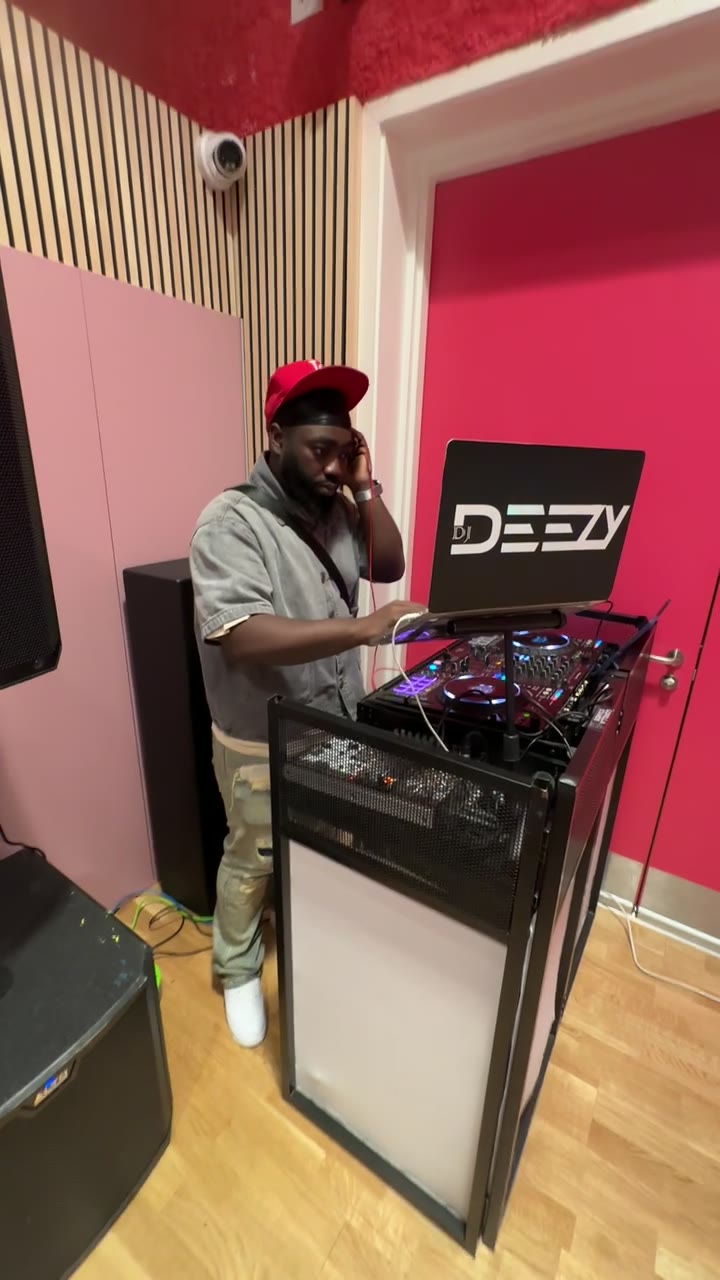 DJ DEEZY in a red cap and headphones mixing on a DJ controller